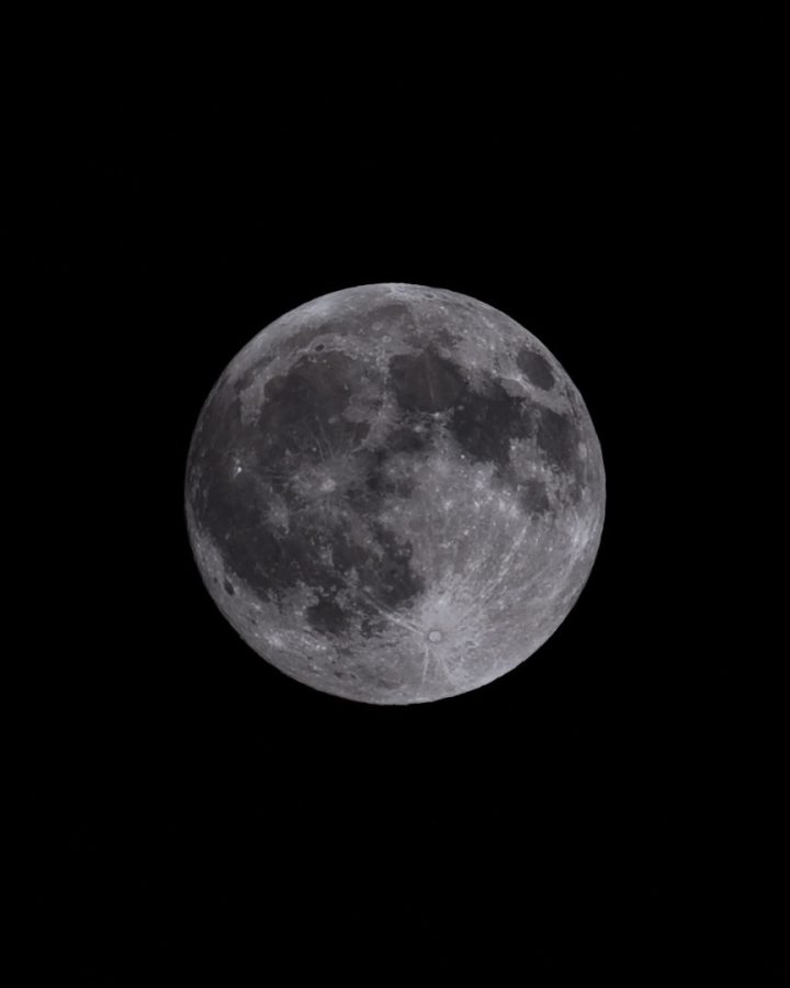 The Moon one night before full: grey maria and bright highlands, with long rays fanning out from the crater Tycho near the bottom.